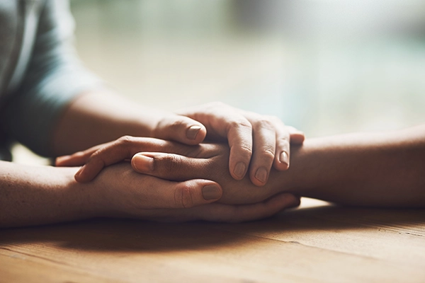 Two people holding hands on a wooden table
