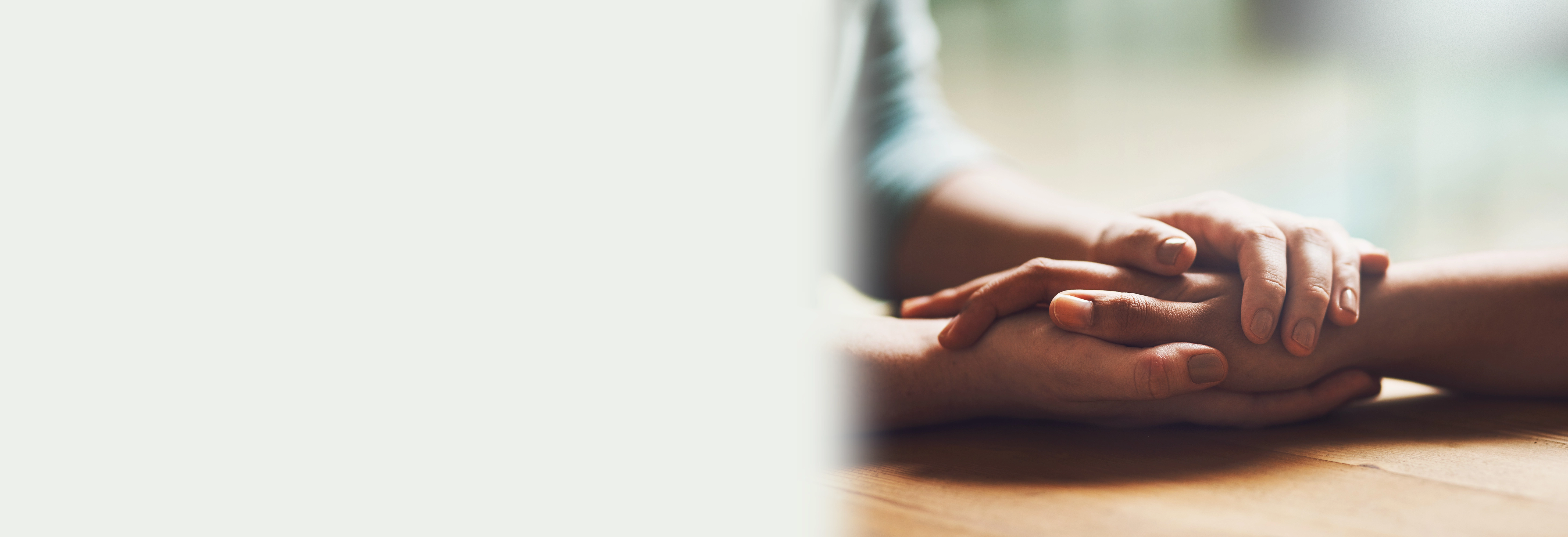 Two people holding hands on a wooden table