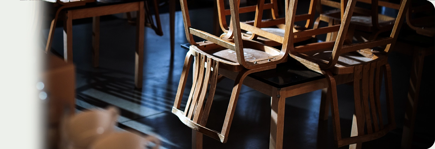 Closed cafe with wooden chairs stacked upside down on tables