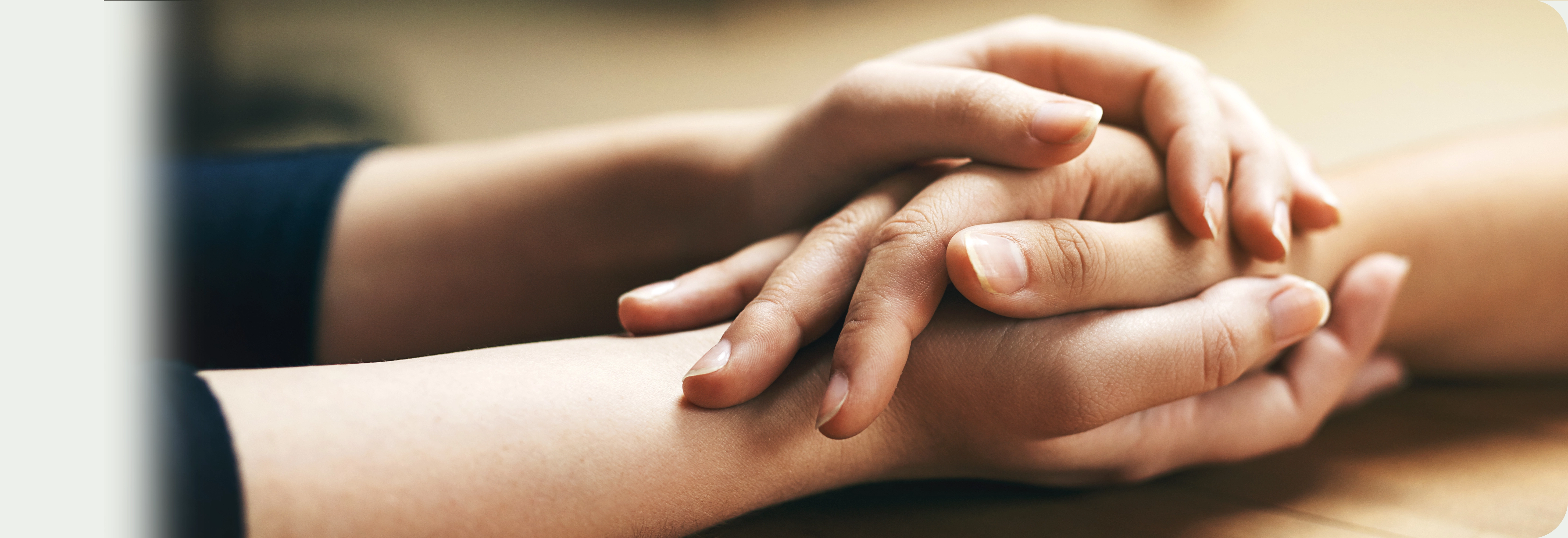 Close-up of one person holding another person’s hand in a supportive gesture