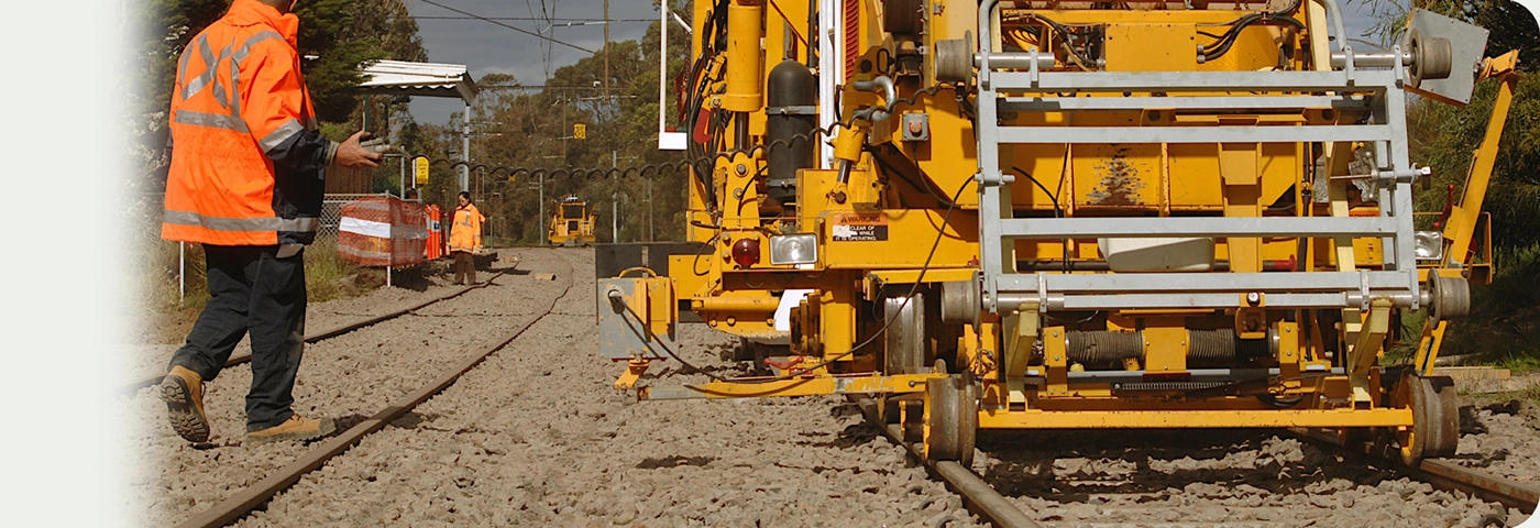 Train track upgrades in Melbourne at Middle Park station and bridge, showing a line shaping and levelling vehicle at work with workers